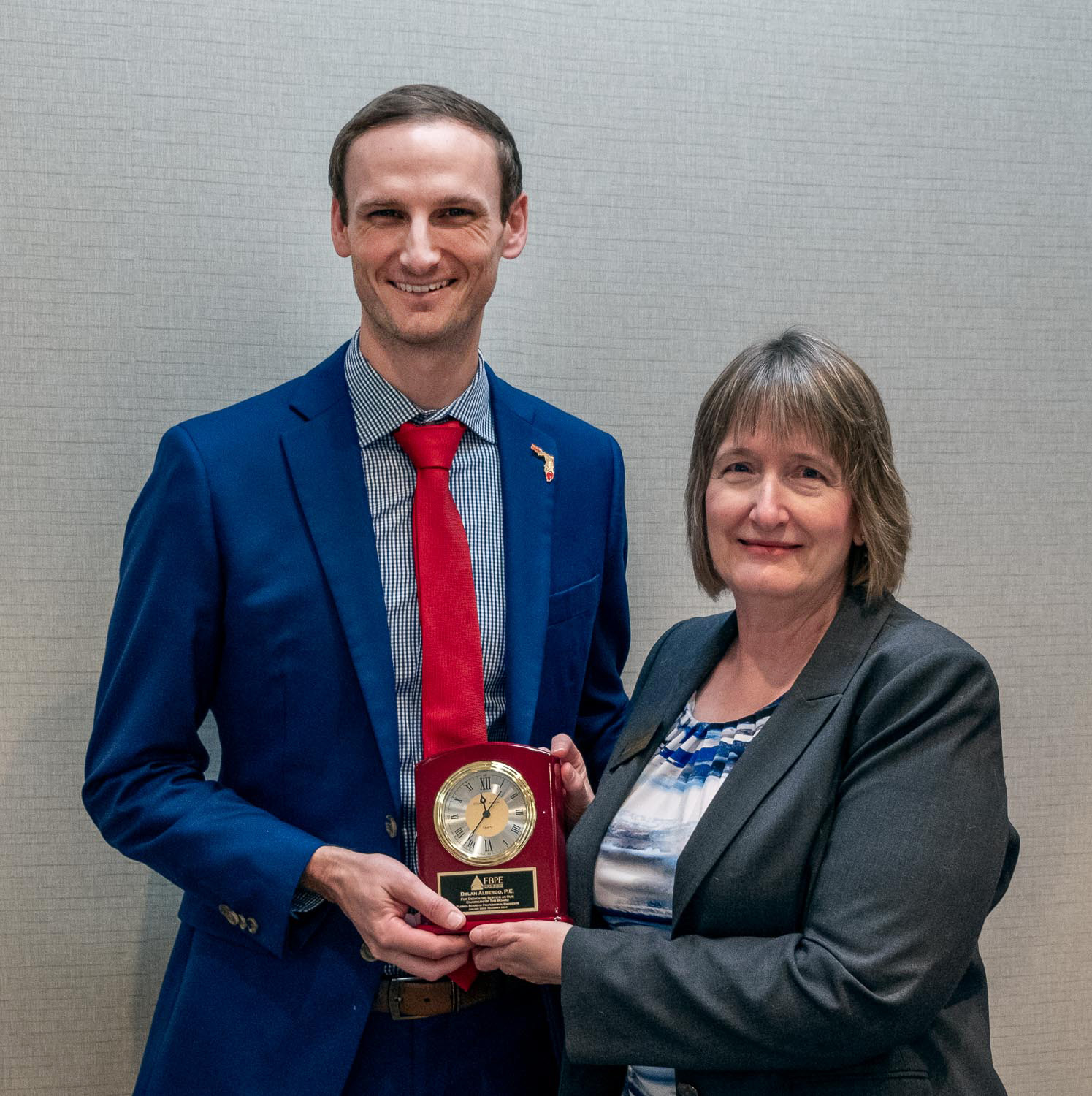 FBPE Chair Denise Ramsey, PE, presents a commemorative clock to outgoing Chair Dylan Albergo, PE.